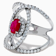 The Ruby Royale 14K White Gold Ruby and Diamond Ring features a central oval ruby with intersecting diamond-encrusted bands, beautifully set against a plain white background.