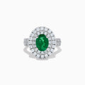 The Brasilica 18K White Gold Emerald and Diamond Double Halo Ring features an oval green emerald encircled by two rows of diamonds and delicate side stones, all set on a white gold band against a white background.