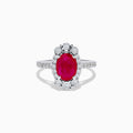 The Ruby Royale 14K White Gold Ruby and Diamond Ring showcases an oval red ruby center, a halo of round white diamonds, and additional diamonds along the band.