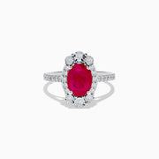 The Ruby Royale 14K White Gold Ruby and Diamond Ring showcases an oval red ruby center, a halo of round white diamonds, and additional diamonds along the band.