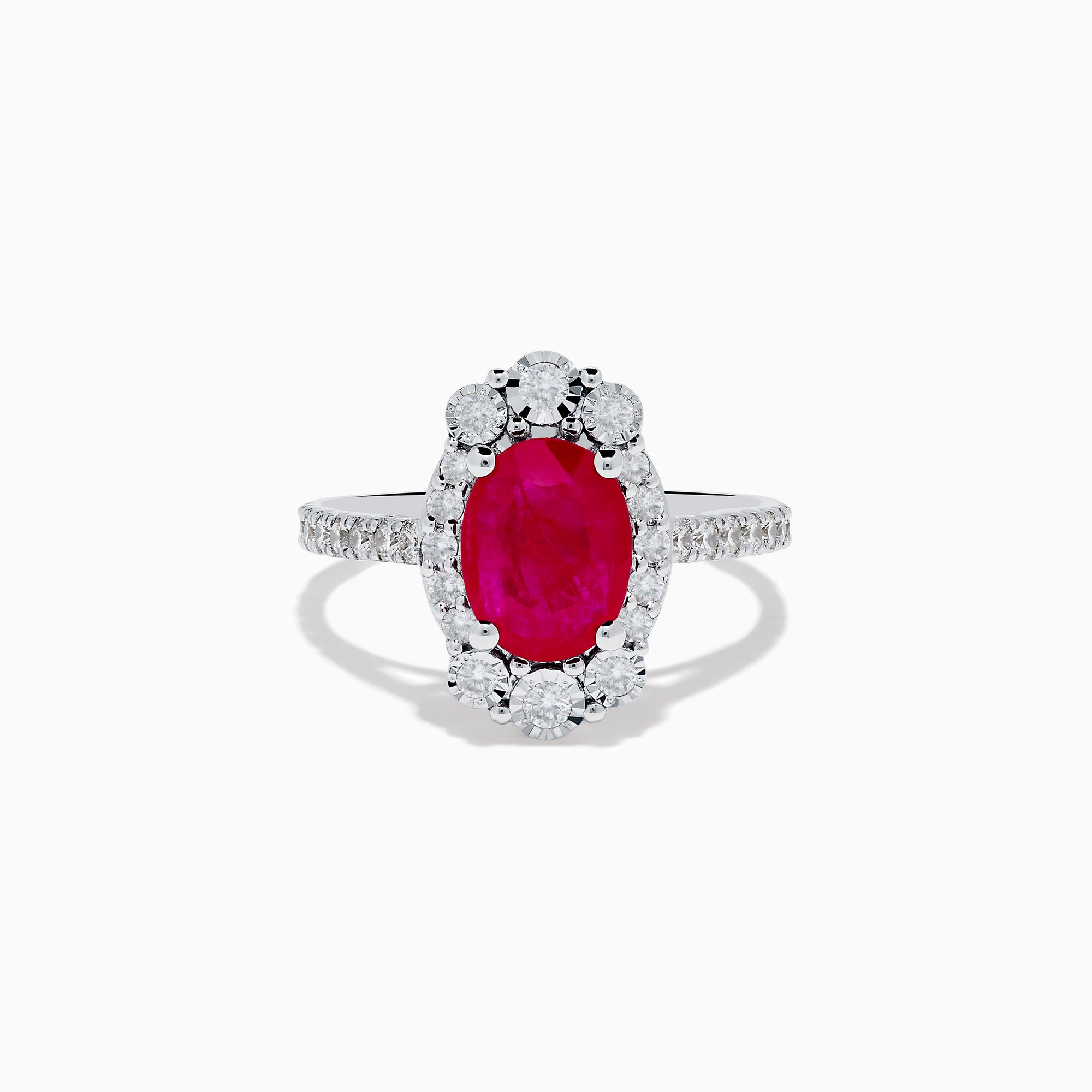 The Ruby Royale 14K White Gold Ruby and Diamond Ring showcases an oval red ruby center, a halo of round white diamonds, and additional diamonds along the band.