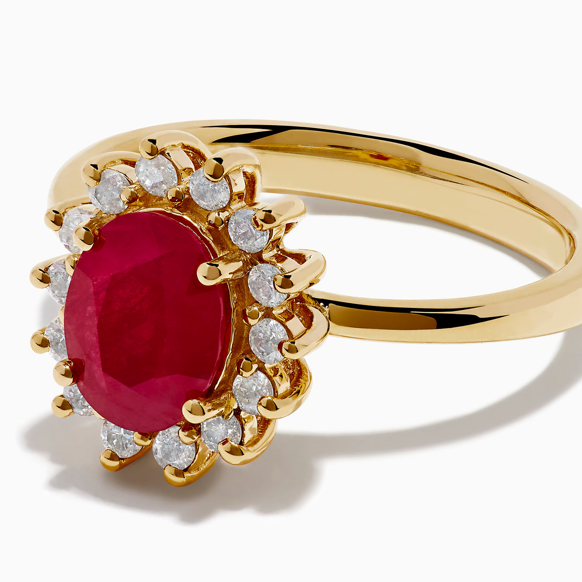 The 14K Yellow Gold Ruby and Diamond Halo Ring showcases an oval ruby center gemstone surrounded by a halo of round white diamonds, set in yellow gold and displayed against a white background.