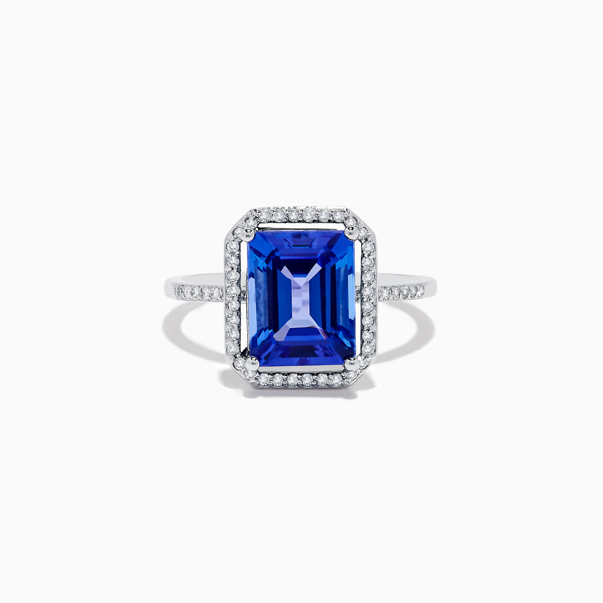 The Nahla Siri 14K White Gold Tanzanite and Diamond Ring features a large emerald-cut blue tanzanite, haloed by small white diamonds with additional diamonds set along the band.
