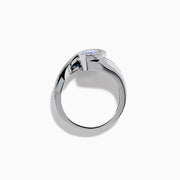 The 14K White Gold Tanzanite and Diamond Oval Swirl Ring features an oval tanzanite center stone accented by sparkling diamonds, all set on a modern, asymmetrical swirl band.