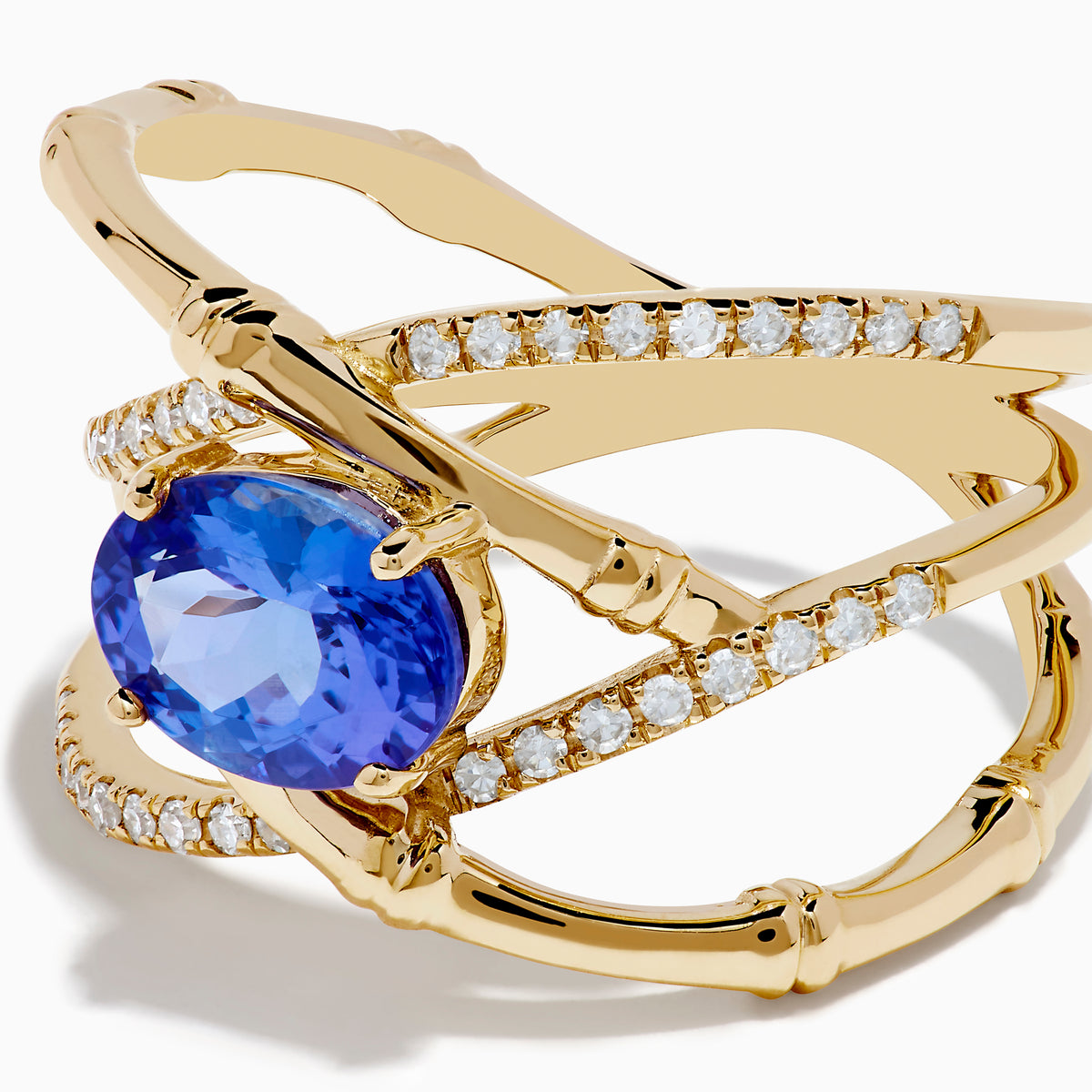 The Nahla 14K Yellow Gold Tanzanite and Diamond Criss Cross Ring features an oval tanzanite centerpiece and sparkling diamond crisscross bands, all set against a white background.