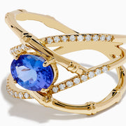 The Nahla 14K Yellow Gold Tanzanite and Diamond Criss Cross Ring features an oval tanzanite centerpiece and sparkling diamond crisscross bands, all set against a white background.