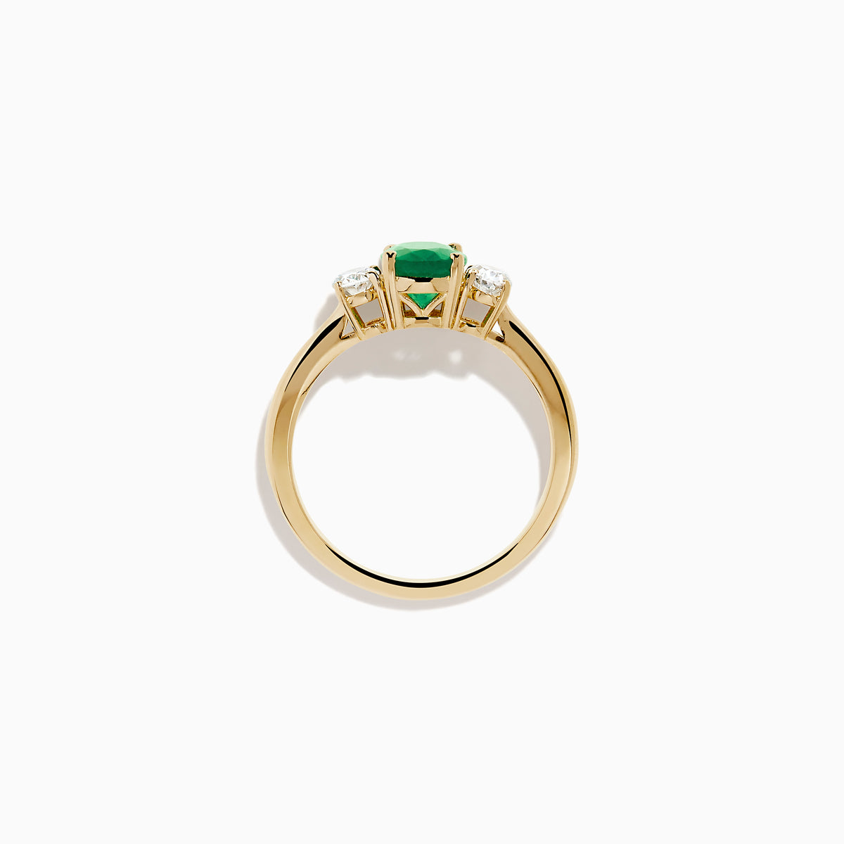 The 14K Yellow Gold Emerald and Diamond Three-Stone Ring showcases an oval green emerald center with two oval white diamonds on each side, all set in 14K yellow gold and displayed against a white background.