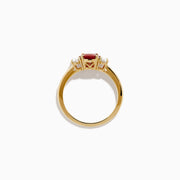 The 14K Yellow Gold Ruby and Diamond Three-Stone Ring showcases a striking oval ruby center with two oval white diamonds, set in yellow gold and displayed on a white background.