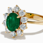 The 14K Yellow Gold Natural Emerald and Diamond Lady Di Ring showcases an oval emerald center surrounded by a halo of round white diamonds.