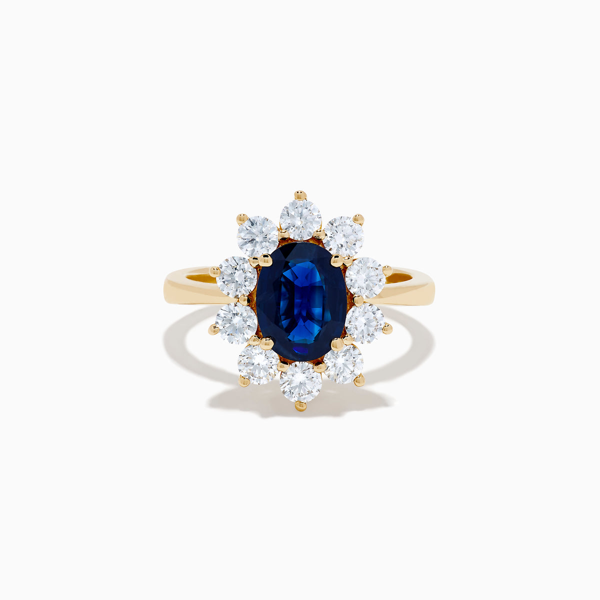 The 14K Yellow Gold Natural Blue Sapphire and Diamond Lady Di Ring features an oval sapphire center, haloed by round white diamonds, shown on a white background.