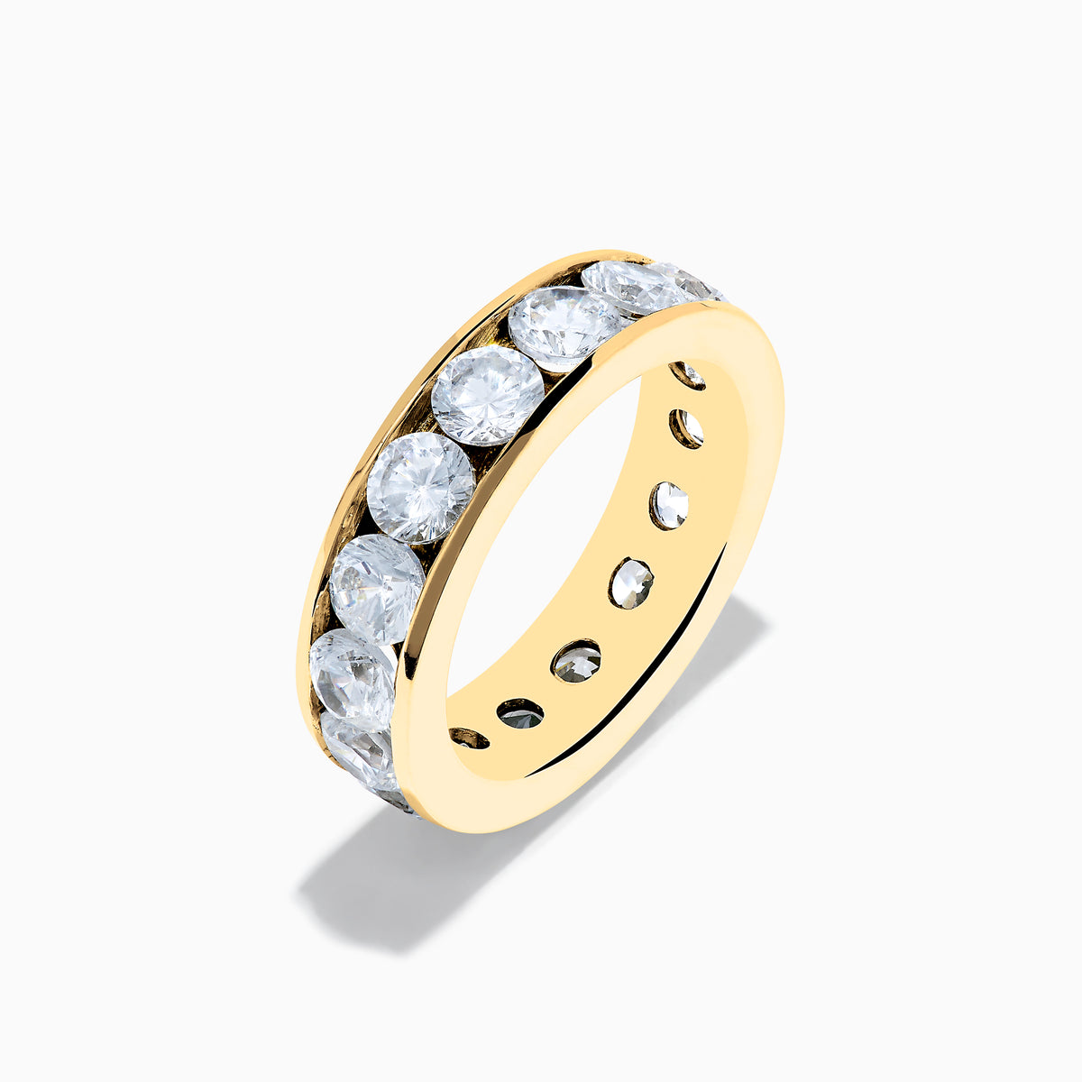 The 14K Yellow Gold Channel Set Diamond Eternity Band, 4.00 TCW, showcases large round diamonds in a continuous channel setting around the band, elegantly displayed on a white background.