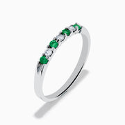 The 14K White Gold 7-Stone Emerald & Diamond Band, 0.25 TCW, showcases alternating round emeralds and diamonds set in a row along the band, displayed on a plain white background.