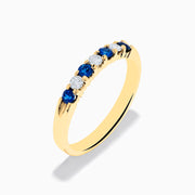 The 14K Yellow Gold 7-Stone Blue Sapphire & Diamond Band (0.50 TCW) features alternating sapphires and diamonds set in a row along the band, making it a striking accessory for any occasion. Displayed on a white background.