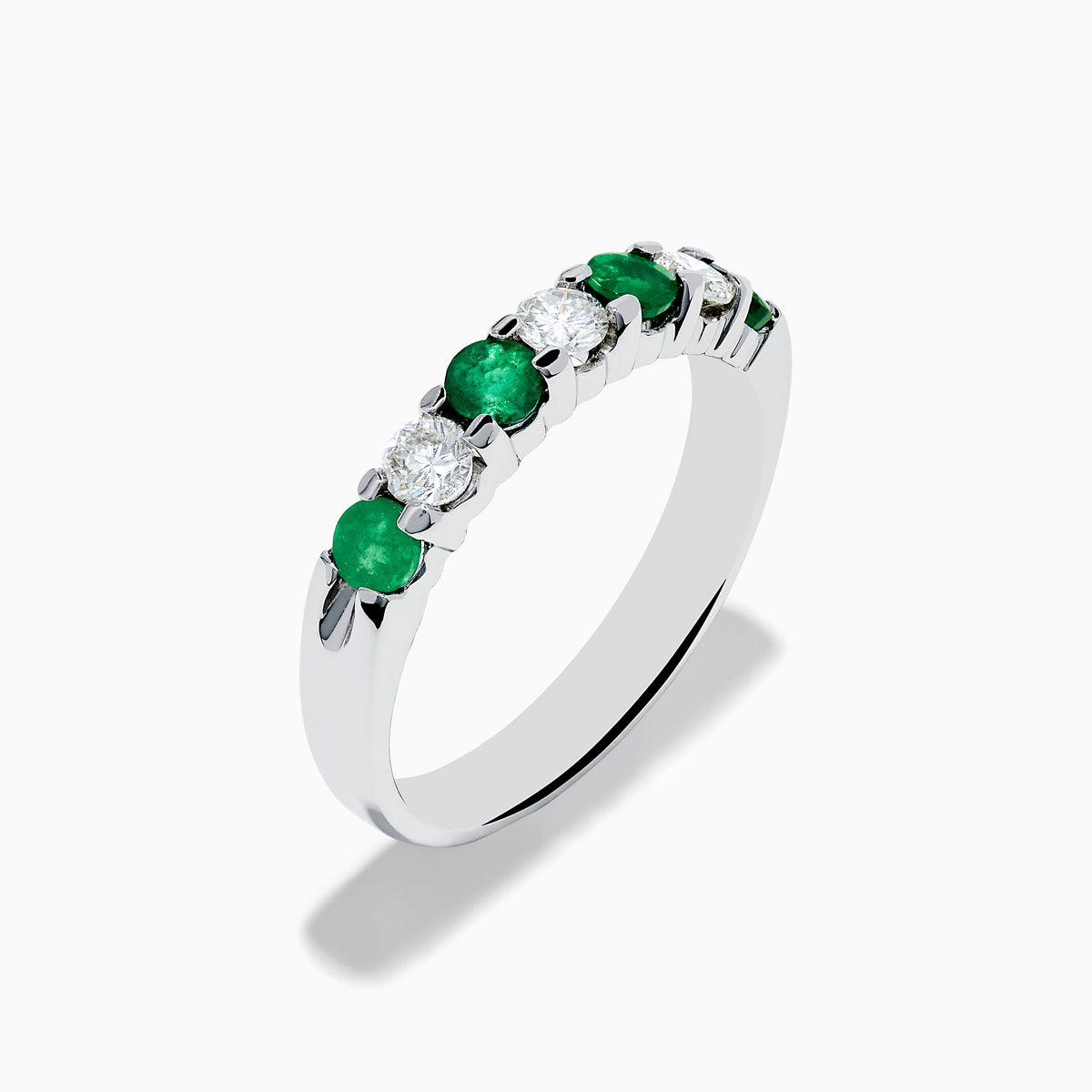The 14K White Gold 7-Stone Emerald & Diamond Band (0.65 TCW) features alternating round emerald and diamond gemstones set in a row, displayed against a white background.