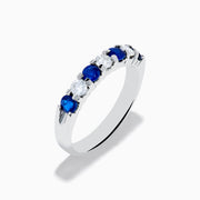 The 14K White Gold 7-Stone Blue Sapphire & Diamond Band, 0.65 TCW, features alternating round blue sapphires and sparkling white diamonds in a row on the band, shown against a white background.