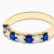 The 14K Yellow Gold 7-Stone Blue Sapphire & Diamond Band, 0.65 TCW, features alternating round blue sapphires and white diamonds set in a row along the band.