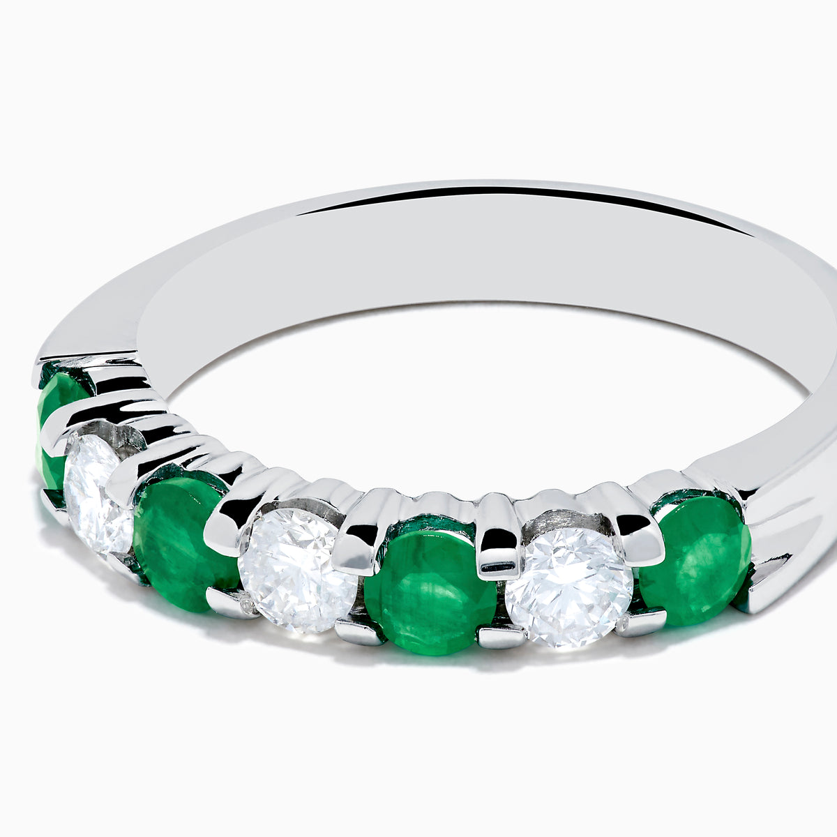 This 14K White Gold 7-Stone Emerald & Diamond Band, 1.00 TCW, features alternating round emeralds and sparkling white diamonds set in a sleek silver band.
