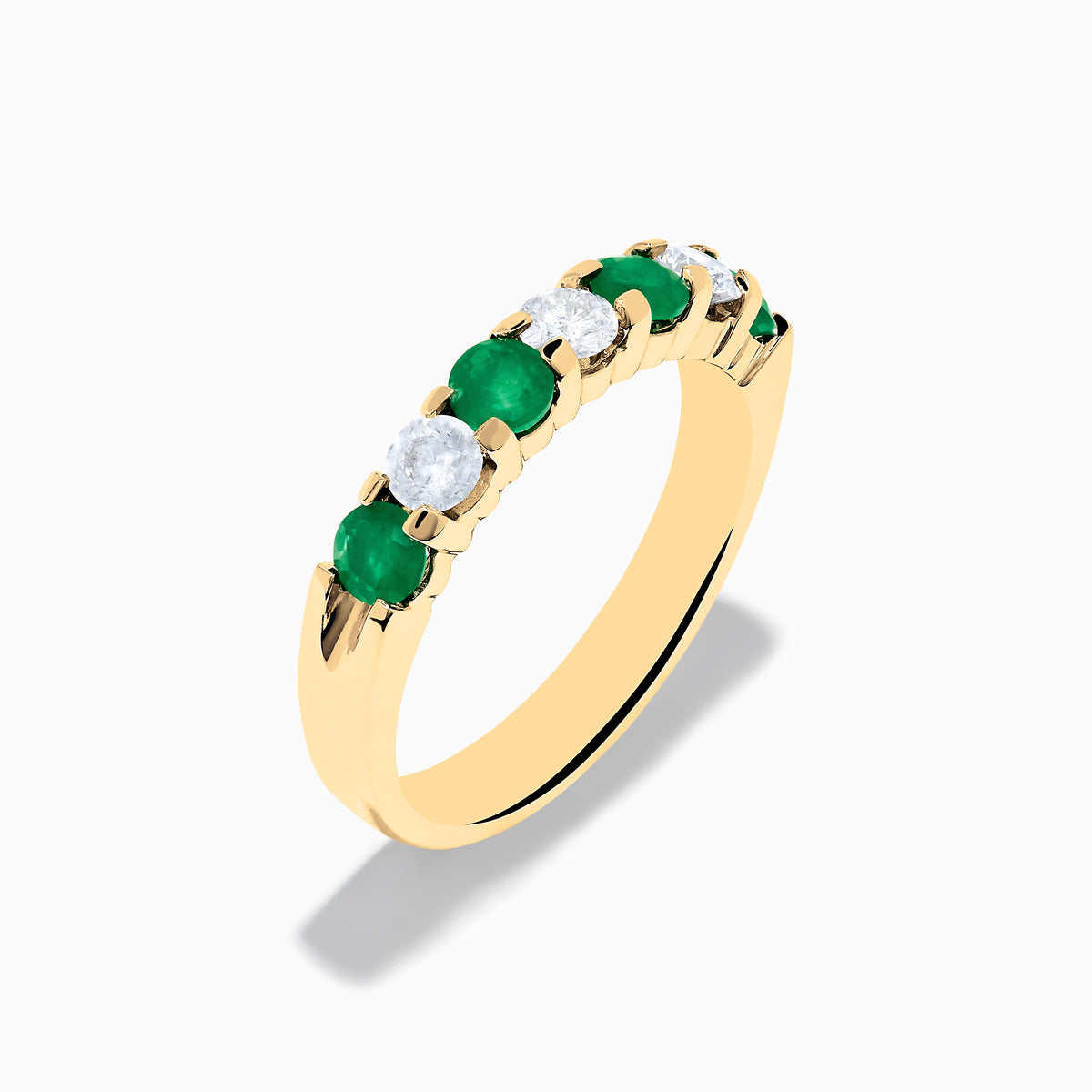 The 14K Yellow Gold 7-Stone Emerald & Diamond Band, 1.00 TCW, features alternating round white diamonds and vibrant emeralds set in a row, shown against a plain white background.