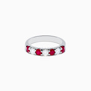 The 14K White Gold 7-Stone Ruby & Diamond Band, 1.00 TCW, showcases alternating round rubies and clear diamonds in a single row along the band, displayed on a white background.