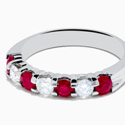 The 14K White Gold 7-Stone Ruby & Diamond Band, 1.00 TCW, showcases alternating round rubies and clear diamonds in a single row along the band, displayed on a white background.