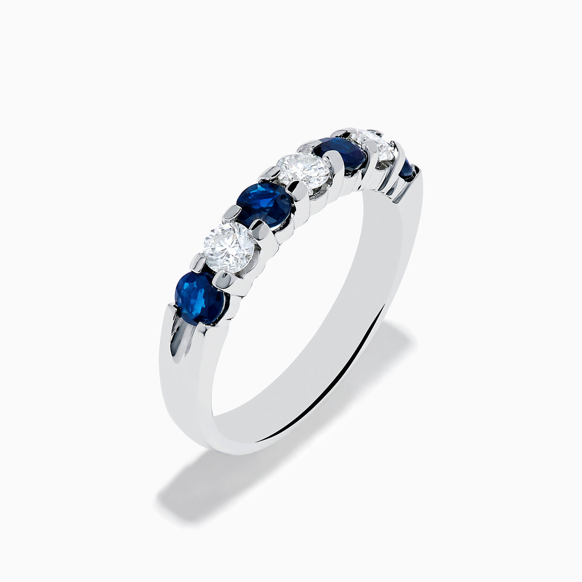 The 14K White Gold 7-Stone Blue Sapphire & Diamond Band, 1.00 TCW, features alternating round blue sapphires and white diamonds, displayed on a plain white background.