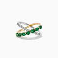 The 14K Two Tone Gold Emerald and Diamond Criss Cross Ring features intertwined yellow gold with green emeralds and white gold with clear round diamonds for a striking, modern look.