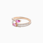 The 14K Rose Gold Pink Sapphire and Diamond Bypass Ring features two pear-shaped pink sapphires at each end and round white diamonds along the band, shown on a white background.
