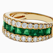 The Brasilica 14K Yellow Gold Emerald and Diamond Wide Band Ring features a symmetrical design with two rows of round diamonds framing horizontally set rectangular green emeralds, offering timeless sophistication.