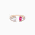 The 14K Rose Gold Pink Sapphire and Diamond Toi Et Moi Ring features a diamond-set band, a rectangular cluster of baguette and round diamonds on one side, and an oval pink sapphire on the other.