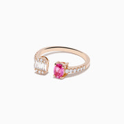 The 14K Rose Gold Pink Sapphire and Diamond Toi Et Moi Ring features a diamond-set band, a rectangular cluster of baguette and round diamonds on one side, and an oval pink sapphire on the other.