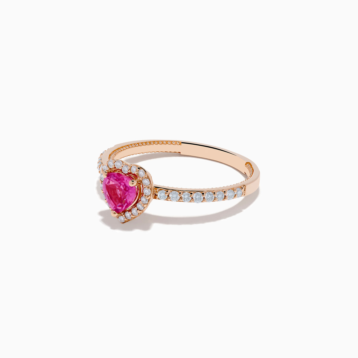 The Novelty 14K Rose Gold Pink Sapphire and Diamond Heart Ring showcases a heart-shaped pink sapphire center, a halo of white diamonds, and extra diamonds accenting the band.