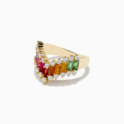 The 14K Yellow Gold Multi Color Sapphire and Diamond Contoured Band Ring showcases sapphire baguettes in various colors bordered by small round diamonds, all set in a chevron shape against a white background.