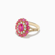 The 14K Yellow Gold Pink Sapphire and Diamond Ring features a large oval pink sapphire center, haloed by round diamonds and pink gemstones, with intricate band detailing.
