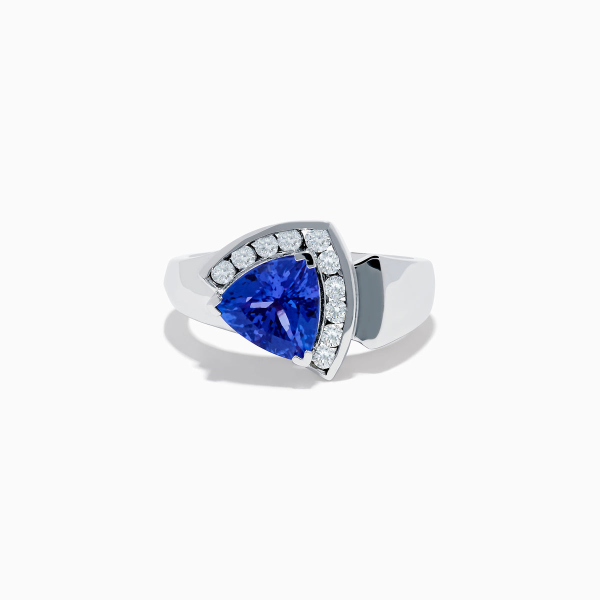 The Nahla Siri 14K White Gold Tanzanite and Diamond Ring showcases a large triangular blue tanzanite framed by a curved row of sparkling white diamonds, set against a white background.