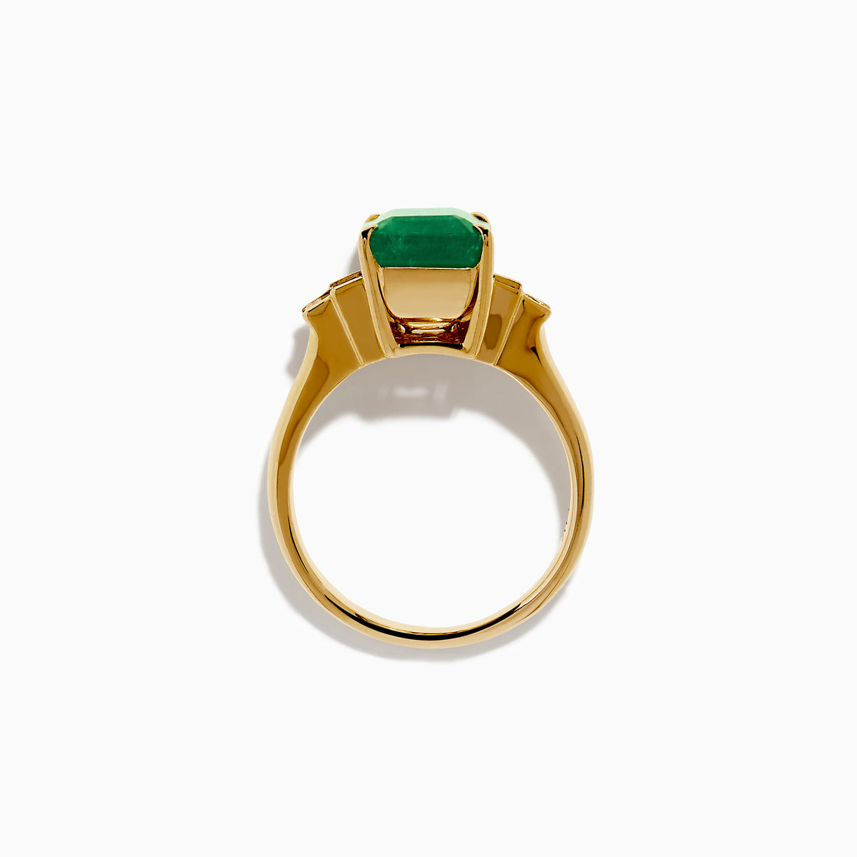 The 14K Yellow Gold Emerald and Diamond Solitaire Ring showcases a vibrant rectangular emerald at its center, accented by two baguette-cut diamonds on each side for a truly elegant look.