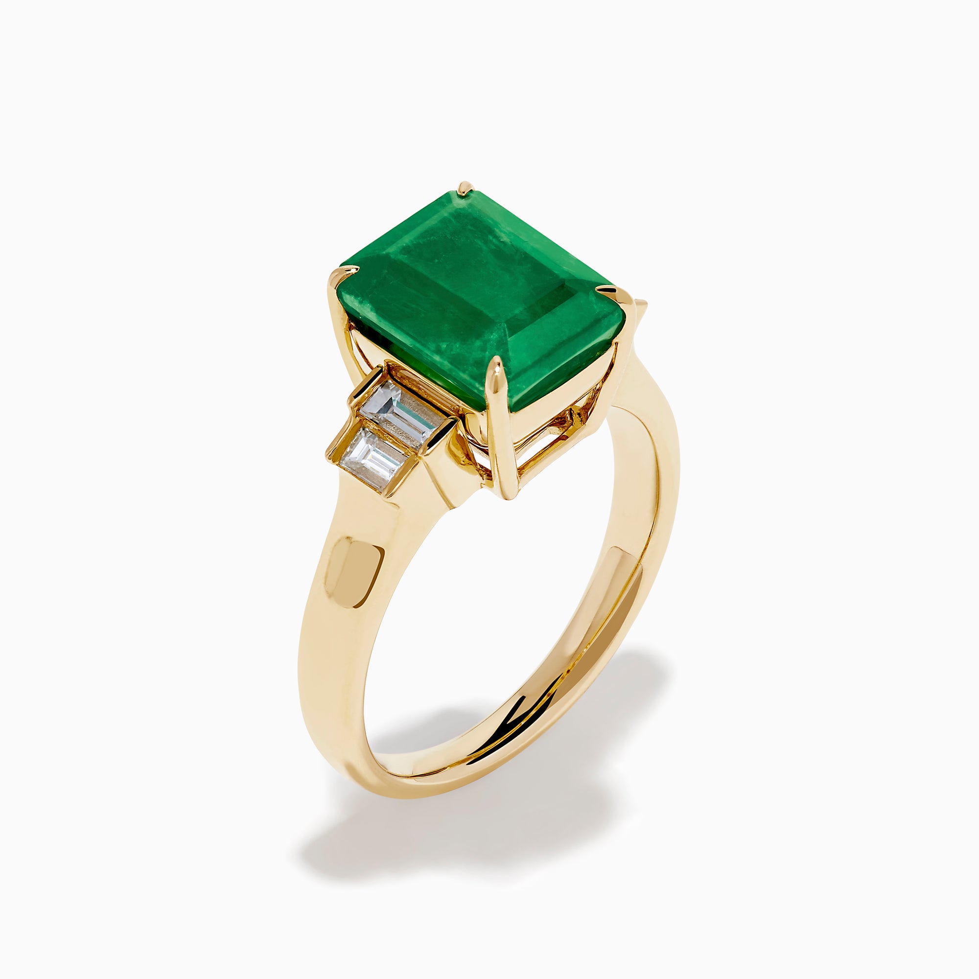 The 14K Yellow Gold Emerald and Diamond Solitaire Ring showcases a vibrant rectangular emerald at its center, accented by two baguette-cut diamonds on each side for a truly elegant look.