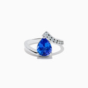 The Nahla Siri 14K White Gold Floating Tanzanite and Diamond Ring features a large pear-shaped blue tanzanite center and a curved band with sparkling round white diamonds on one side, set against a plain white background.