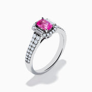 The 14K White Gold Pink Sapphire and Diamond Halo Ring showcases a vivid oval pink sapphire, encircled by a diamond halo with extra diamonds set along its elegant double band.