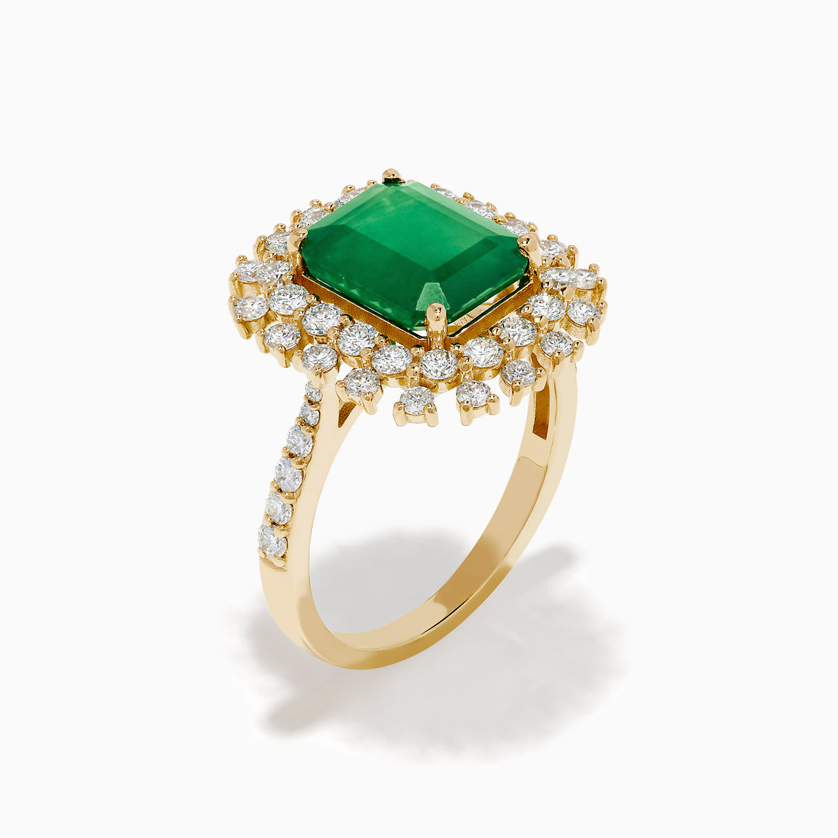 The 14K Yellow Gold Emerald and Diamond Halo Cocktail Ring showcases a large rectangular green emerald at the center, surrounded by a sparkling double halo of round white diamonds.