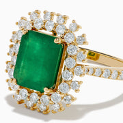 The 14K Yellow Gold Emerald and Diamond Halo Cocktail Ring showcases a large rectangular green emerald at the center, surrounded by a sparkling double halo of round white diamonds.