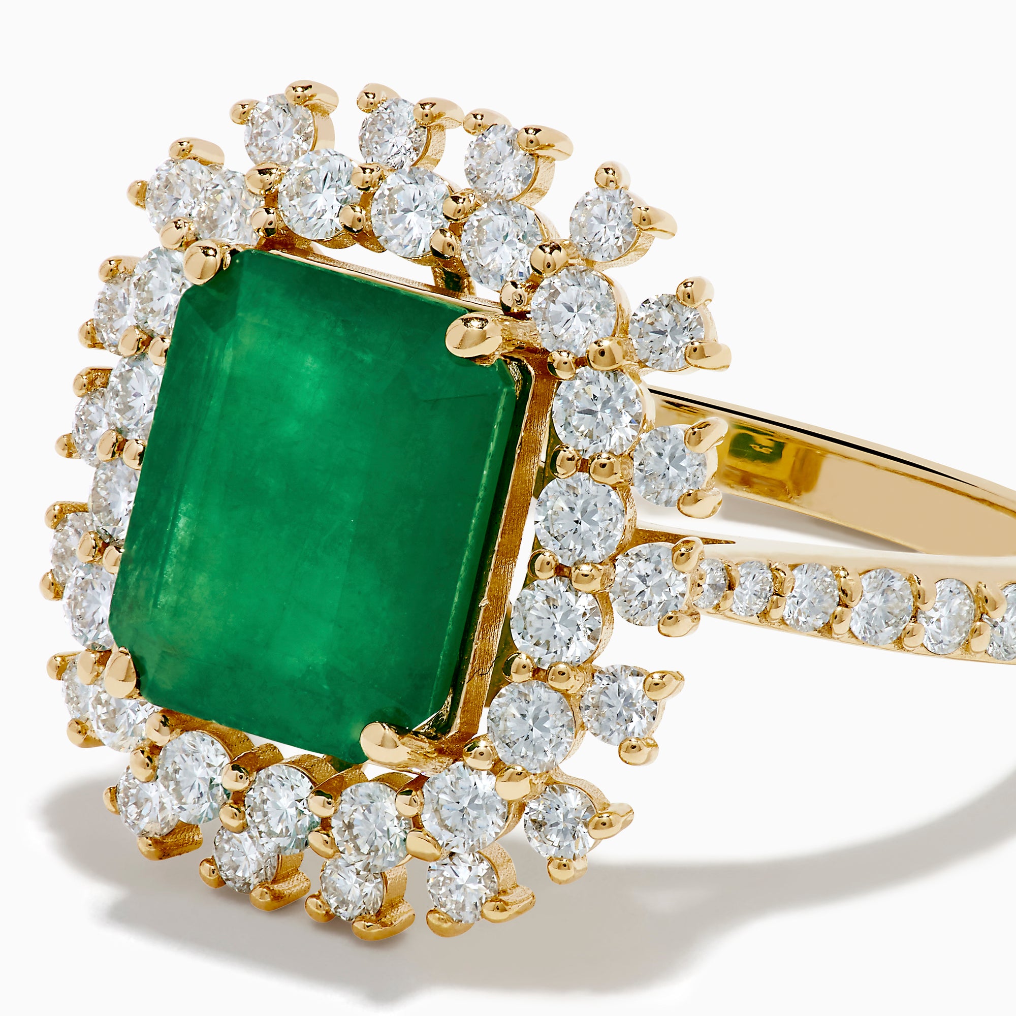 The 14K Yellow Gold Emerald and Diamond Halo Cocktail Ring showcases a large rectangular green emerald at the center, surrounded by a sparkling double halo of round white diamonds.