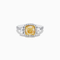 The Canare 18K Two Tone Gold White and Yellow Diamond Ring features a cushion-cut yellow diamond center, framed by a halo of white diamonds and more diamonds set along the band in elegant white gold.