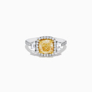 The Canare 18K Two Tone Gold White and Yellow Diamond Ring features a cushion-cut yellow diamond center, framed by a halo of white diamonds and more diamonds set along the band in elegant white gold.