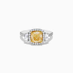 The Canare 18K Two Tone Gold White and Yellow Diamond Ring features a cushion-cut yellow diamond center, framed by a halo of white diamonds and more diamonds set along the band in elegant white gold.