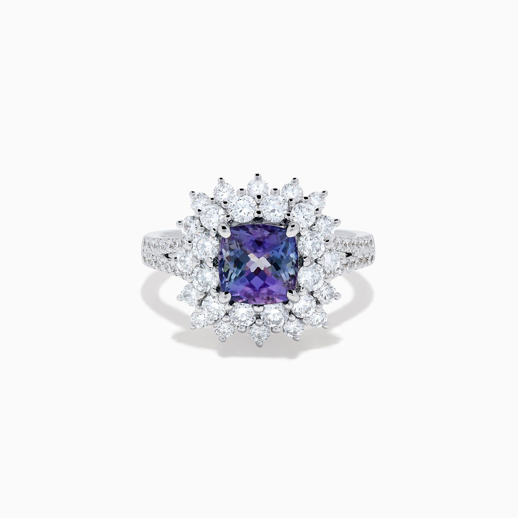 The 18K White Gold GIA Certified Zoisite and Diamond Ring features a cushion-cut blue-purple zoisite center stone with a starburst diamond halo, creating a striking look against the white gold setting.