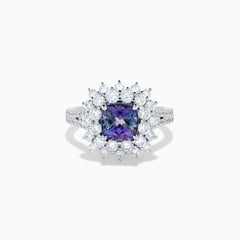 The 18K White Gold GIA Certified Zoisite and Diamond Ring features a cushion-cut blue-purple zoisite center stone with a starburst diamond halo, creating a striking look against the white gold setting.