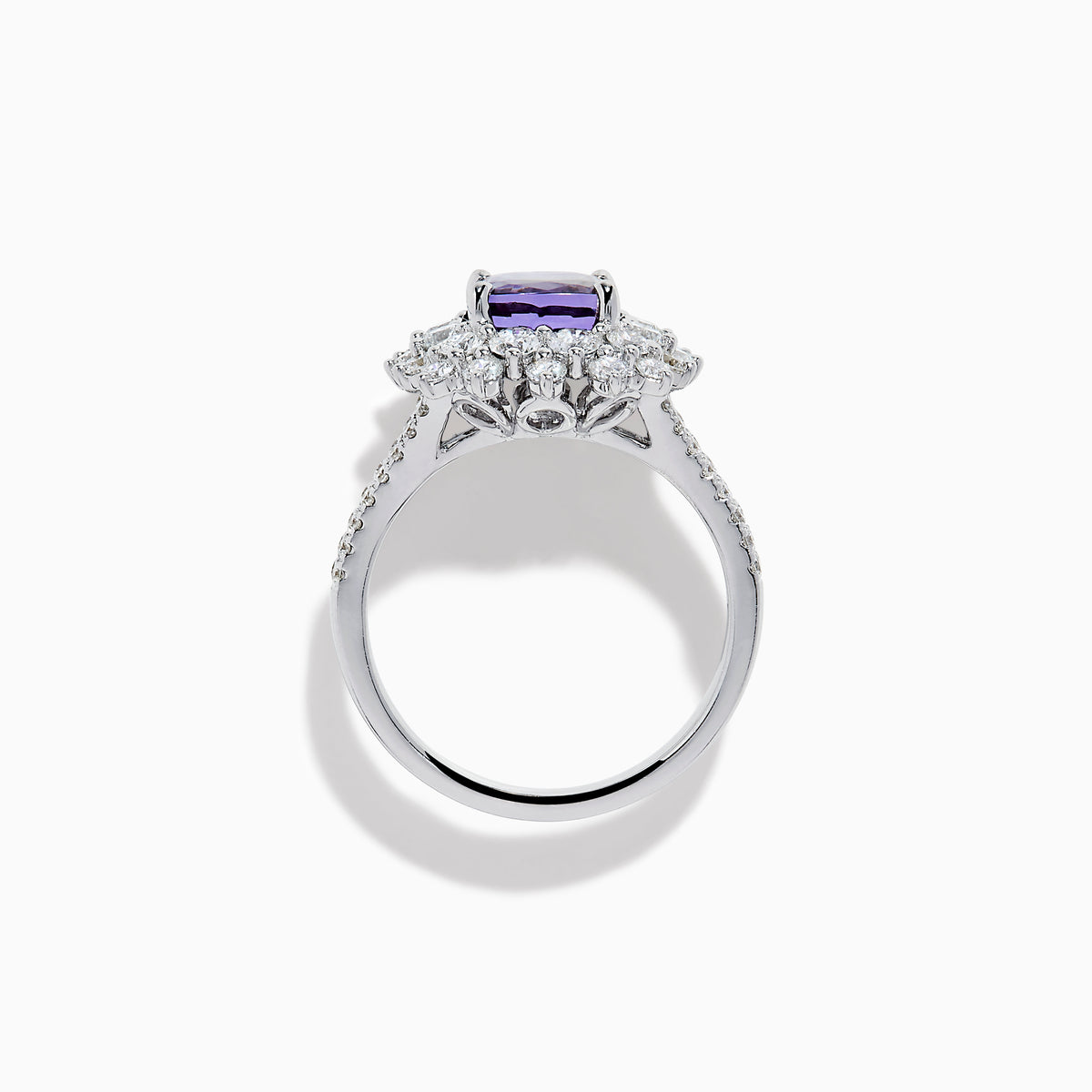 The 18K White Gold GIA Certified Zoisite and Diamond Ring features a cushion-cut blue-purple zoisite center stone with a starburst diamond halo, creating a striking look against the white gold setting.