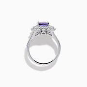 The 18K White Gold GIA Certified Zoisite and Diamond Ring features a cushion-cut blue-purple zoisite center stone with a starburst diamond halo, creating a striking look against the white gold setting.