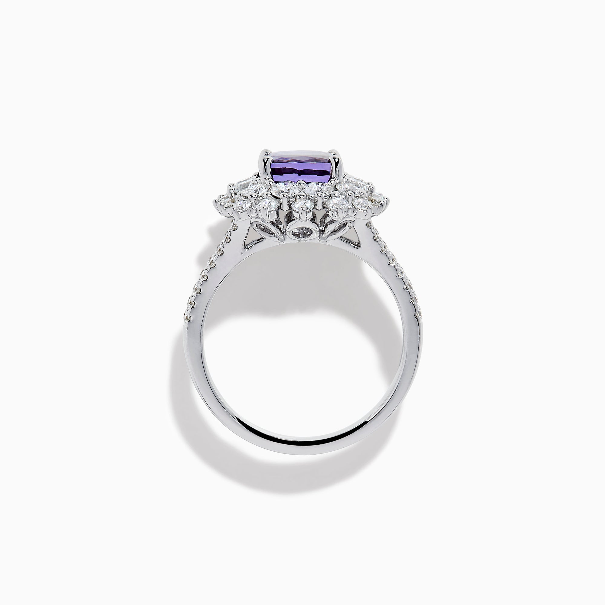 The 18K White Gold GIA Certified Zoisite and Diamond Ring features a cushion-cut blue-purple zoisite center stone with a starburst diamond halo, creating a striking look against the white gold setting.