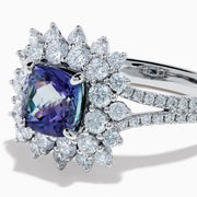 The 18K White Gold GIA Certified Zoisite and Diamond Ring features a cushion-cut blue-purple zoisite center stone with a starburst diamond halo, creating a striking look against the white gold setting.